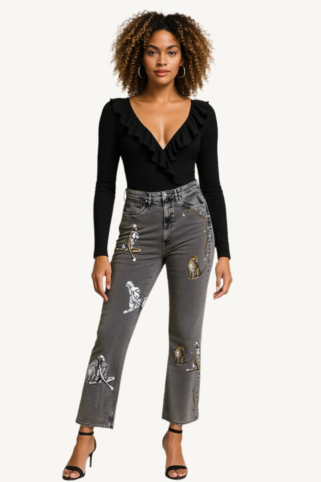Woman wearing a black ruffled top and gray jeans with patches on a beige background