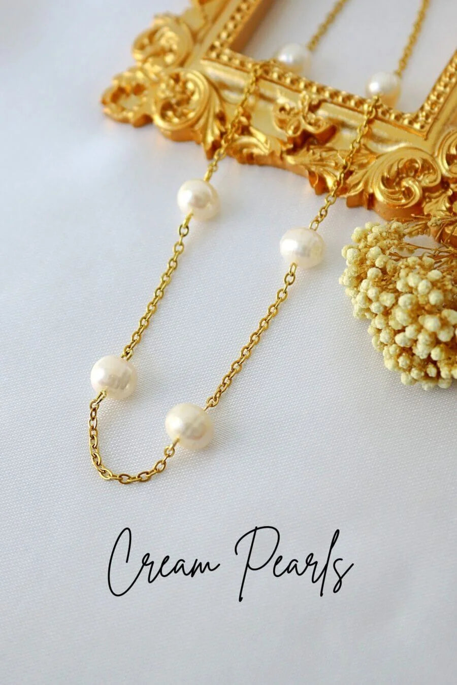 Gold chain necklace with cream pearls on a white background
