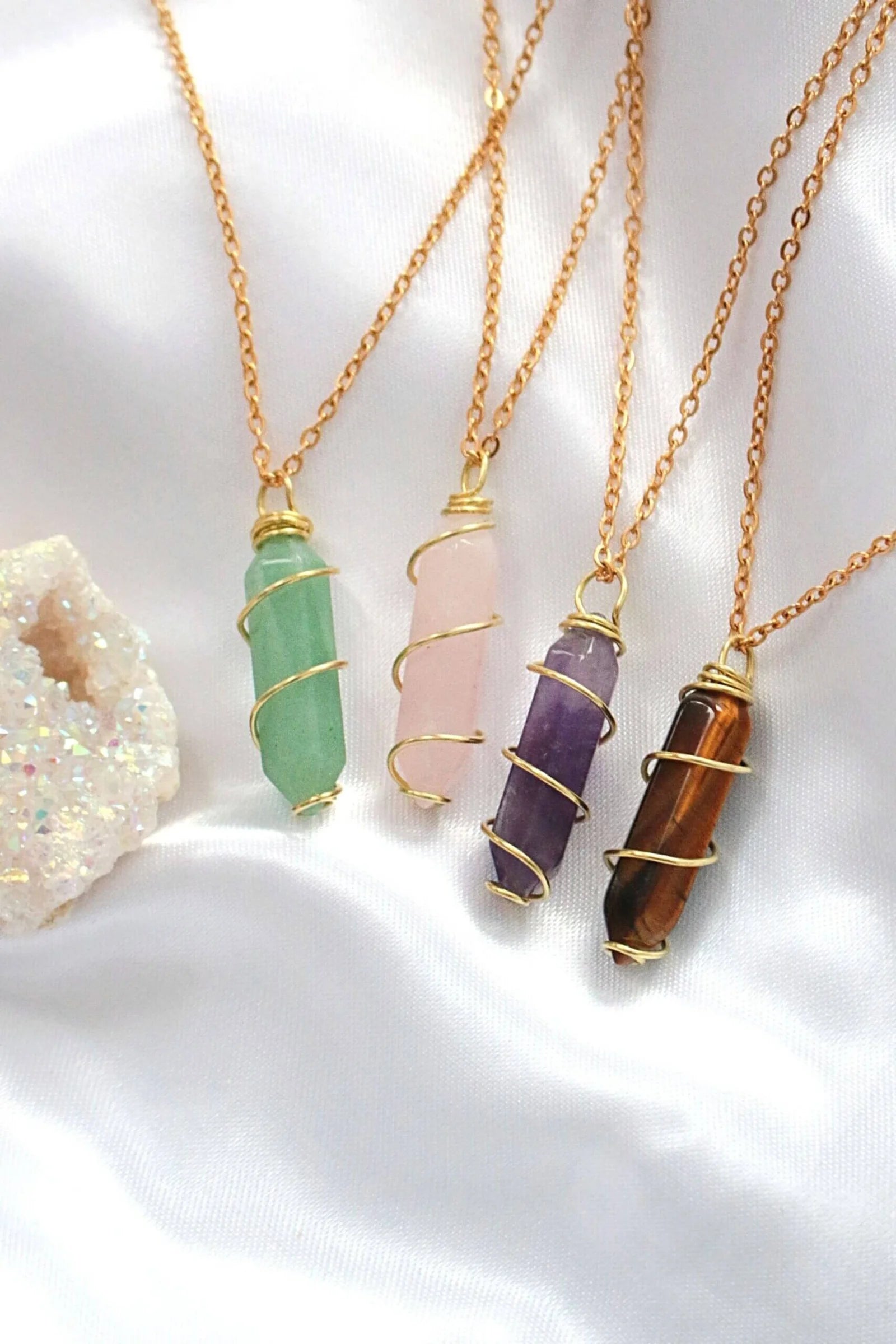 Four gold necklaces with different colored gemstone pendants on a white background