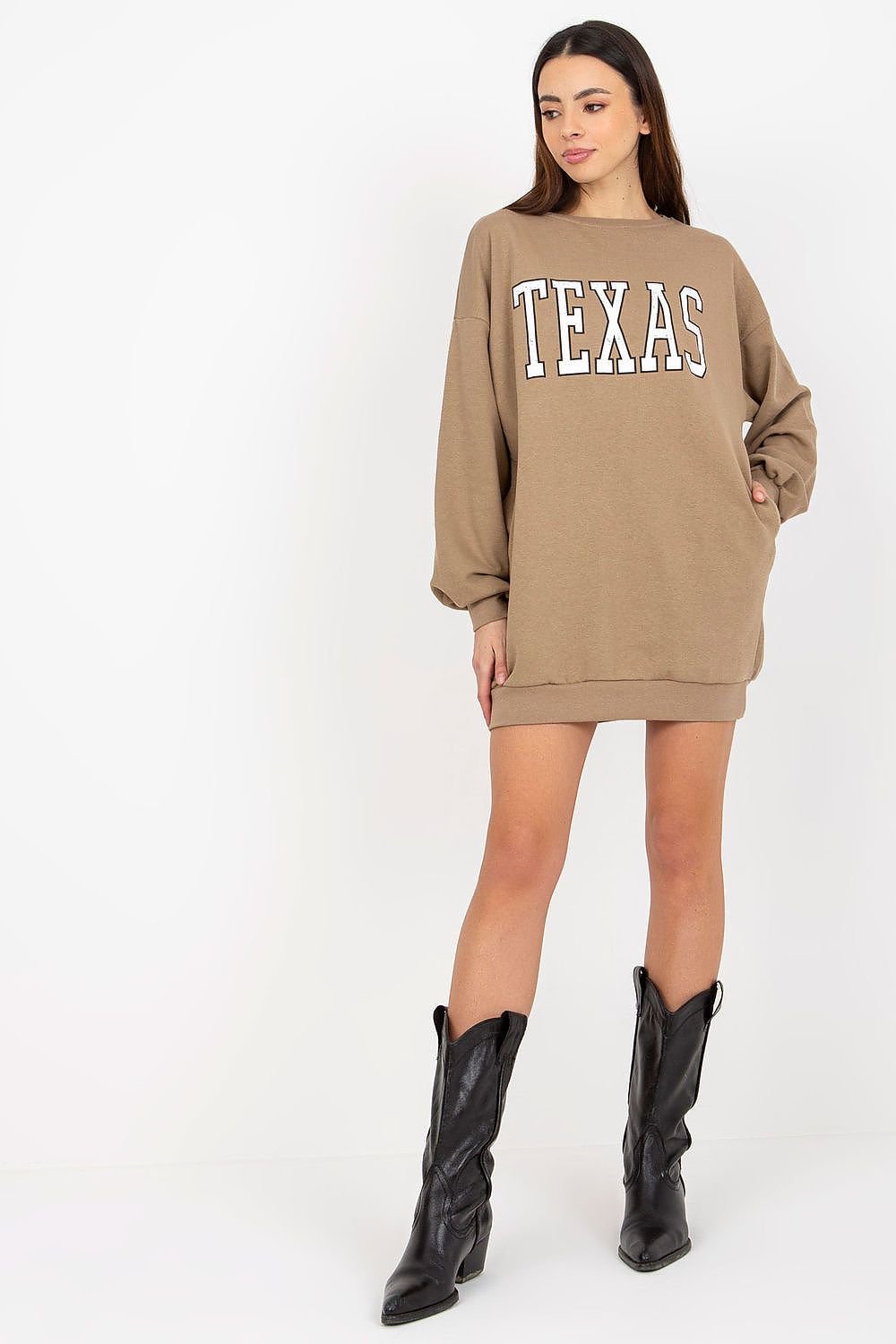Woman wearing a beige sweatshirt dress with 'TEXAS' text and black cowboy boots on a white background