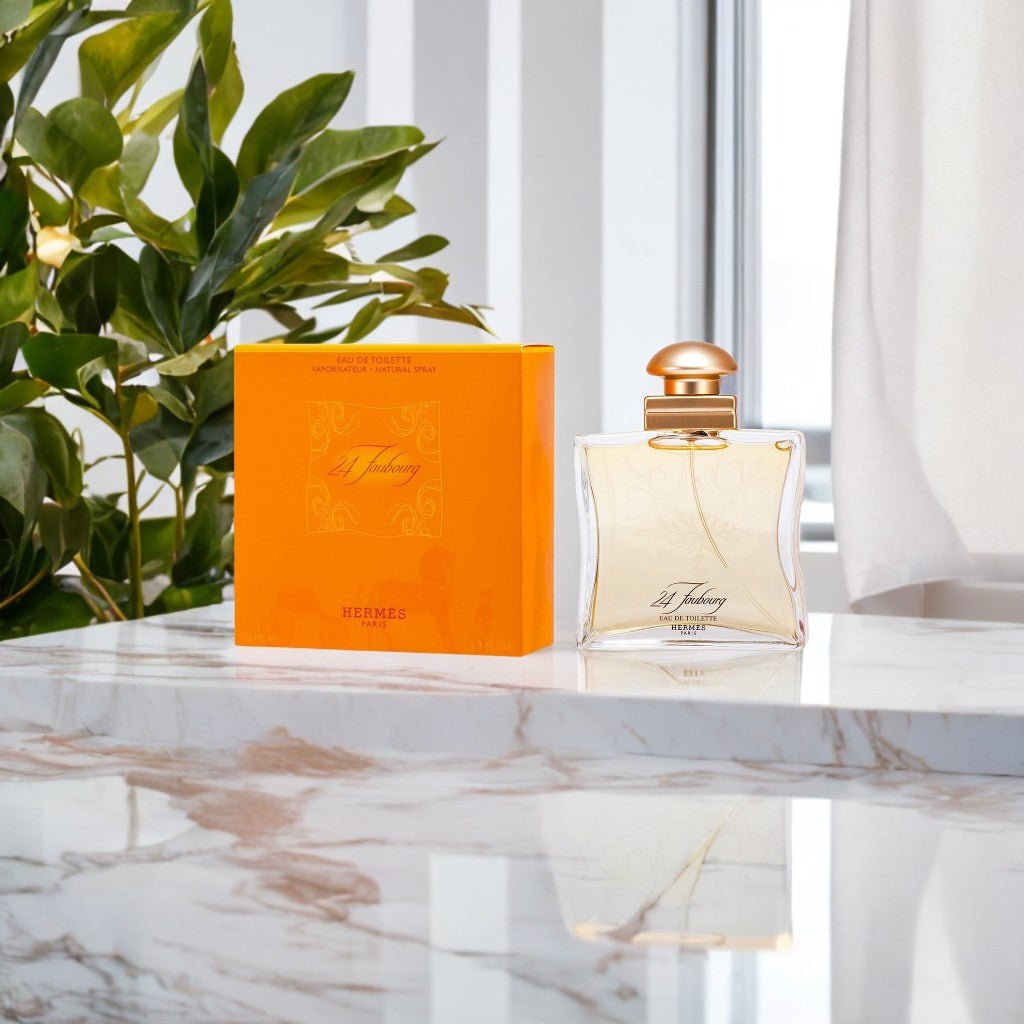 "Hermès 24 Faubourg 3.3 oz Eau de Toilette Spray for Women – elegant square glass bottle with golden-yellow fragrance, adorned with a gold cap, presented alongside its signature orange Hermès box."