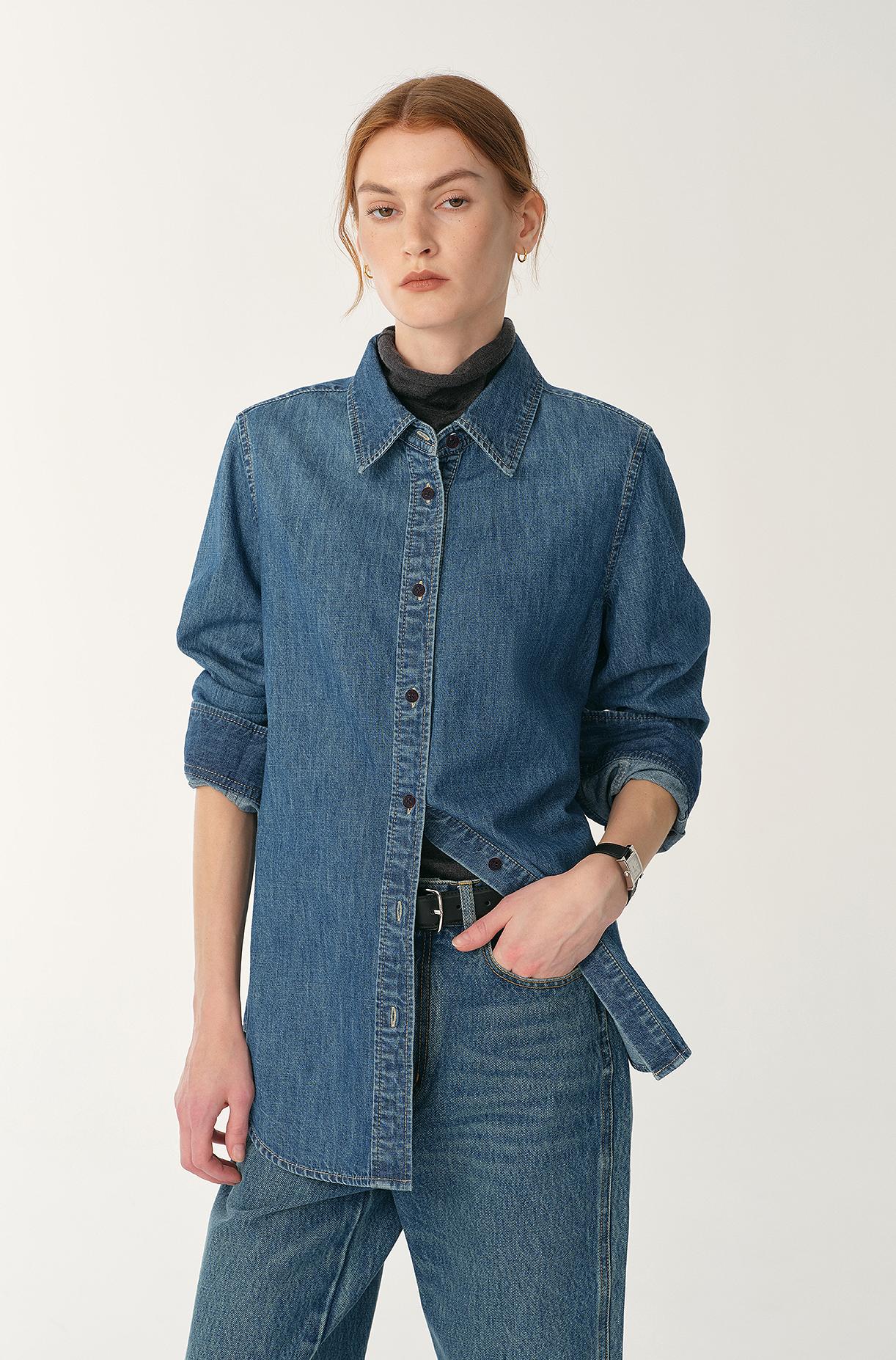 Person wearing a blue denim jacket and jeans on a white background