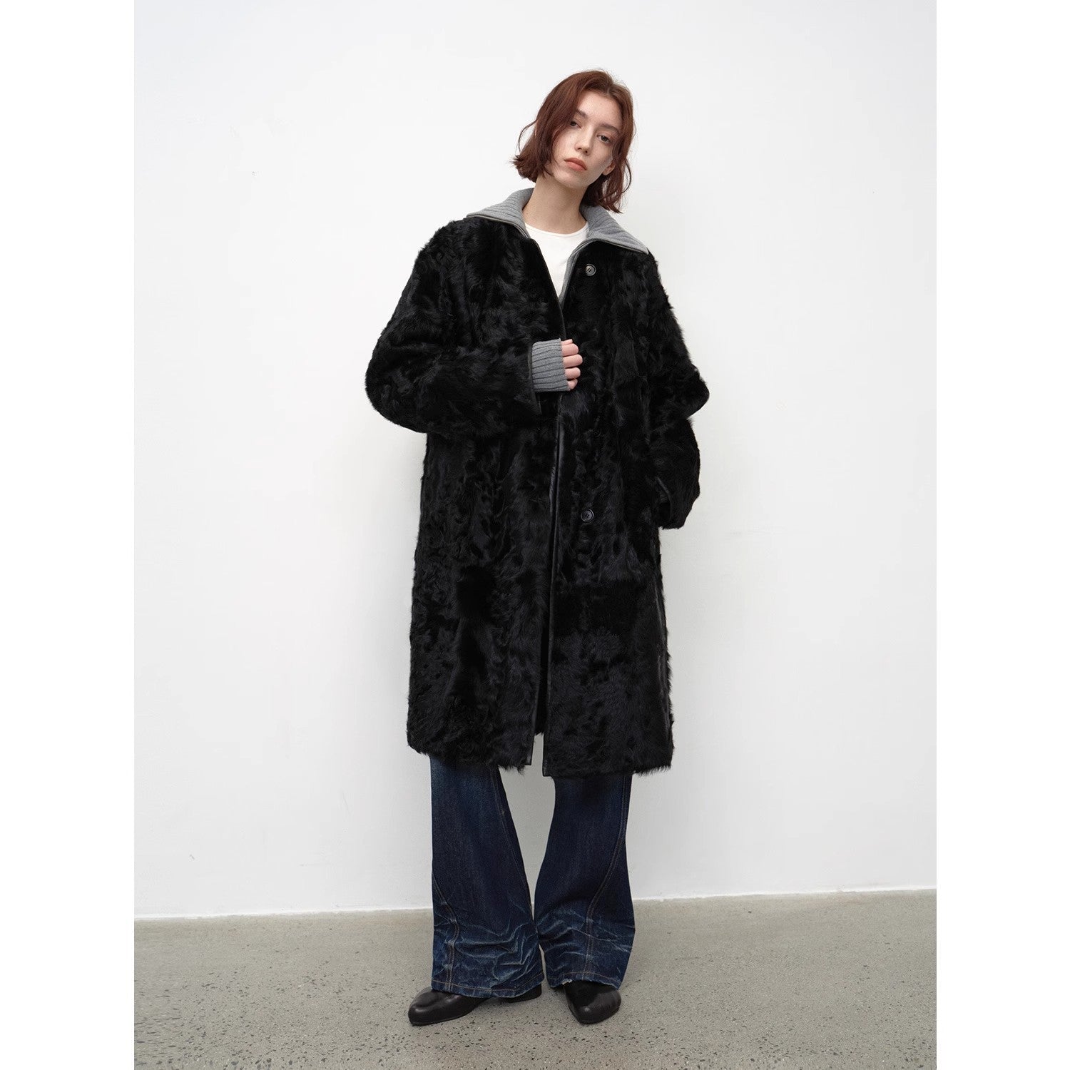 Person wearing a black fur coat against a white background
