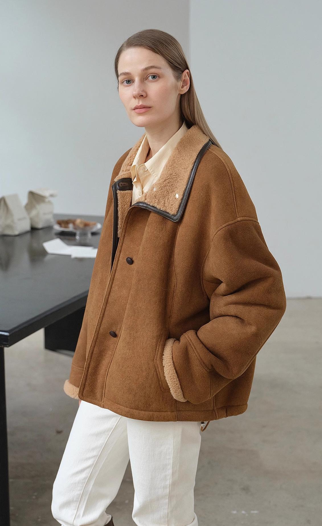 Person wearing a brown coat with a fur collar in an indoor setting