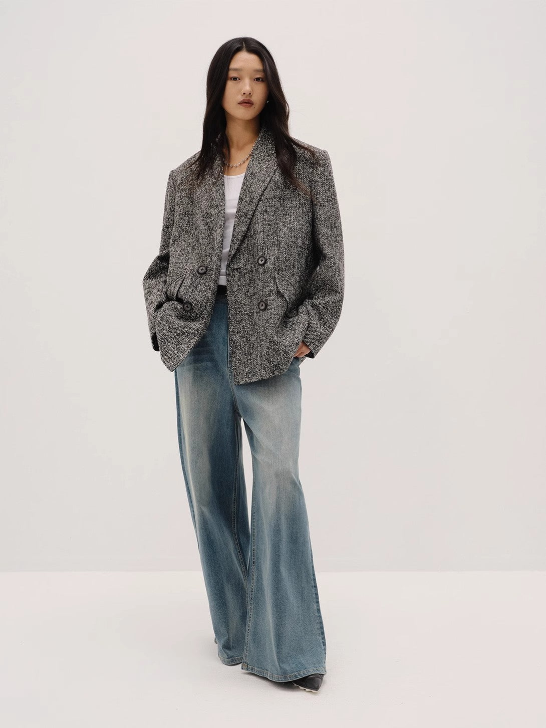 Person wearing a textured blazer and wide-leg jeans on a white background