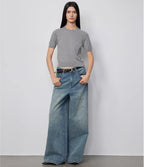 Person wearing a gray t-shirt and blue jeans against a white background