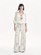 Person wearing a white blouse and patterned pants on a white background