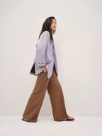 Woman wearing a light gray blazer and brown pants on a white background