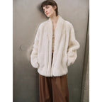 Person wearing a white fur coat against a neutral background