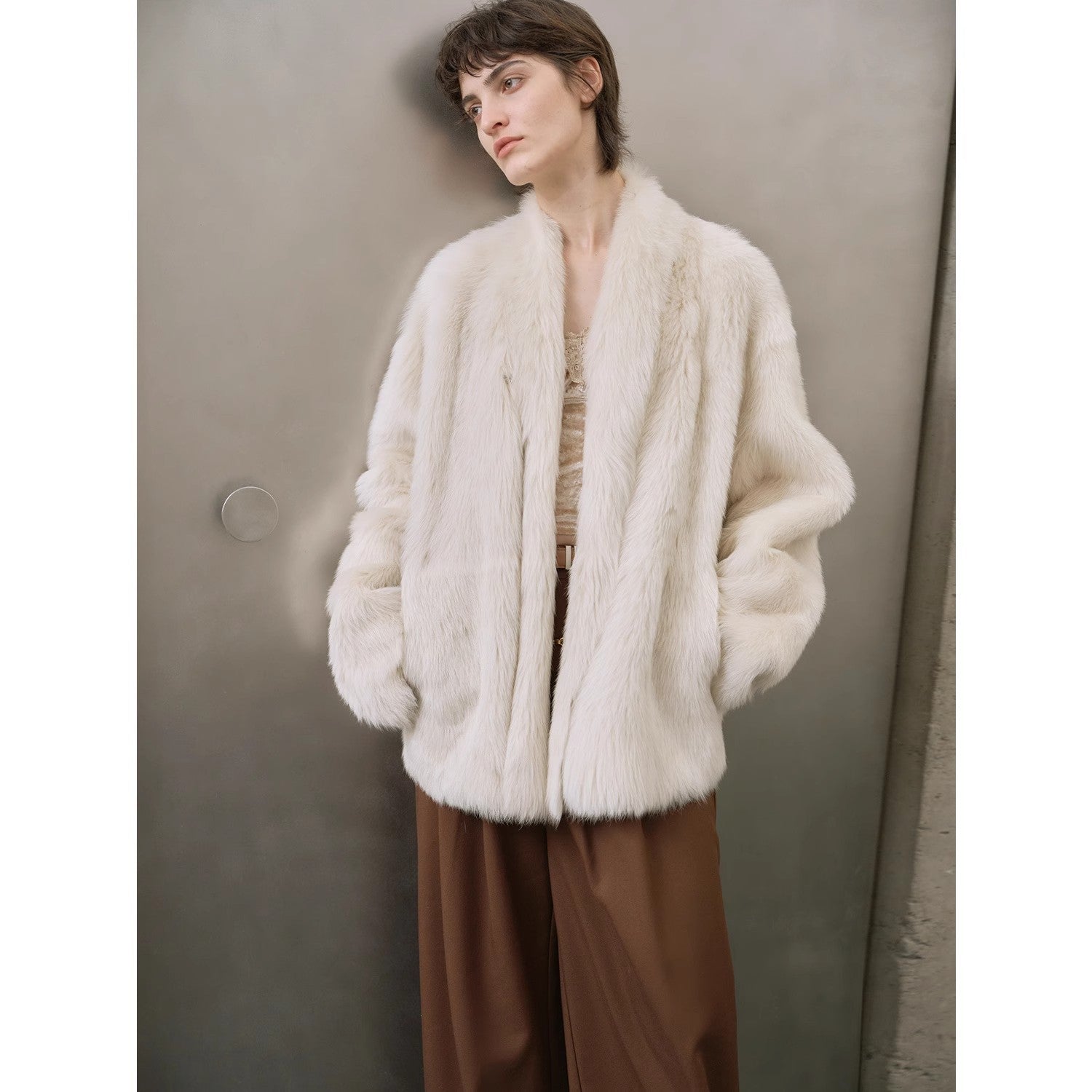 Person wearing a white fur coat against a neutral background