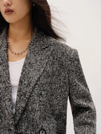 Person wearing a textured blazer over a white top on a plain background