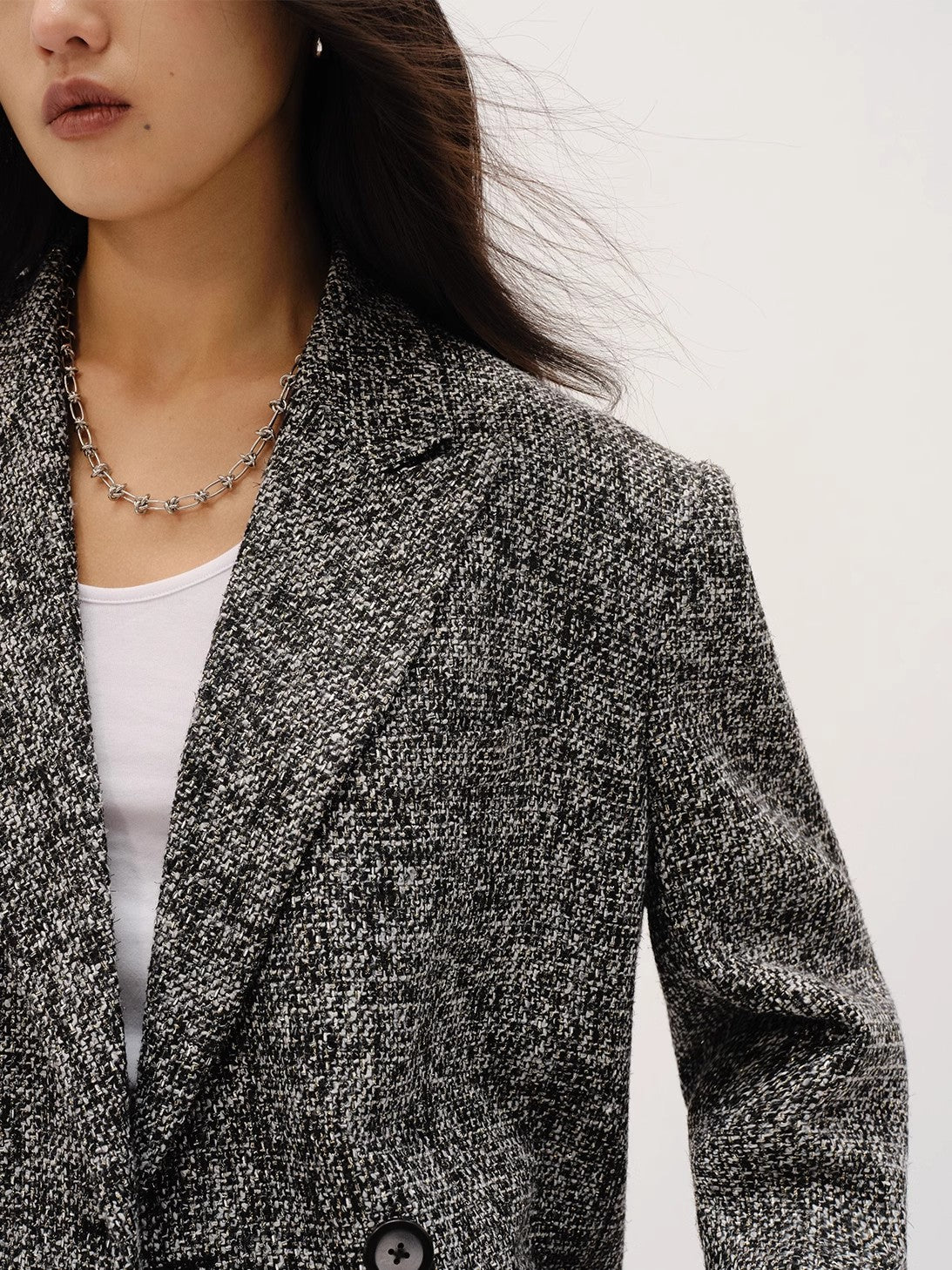 Person wearing a textured blazer over a white top on a plain background