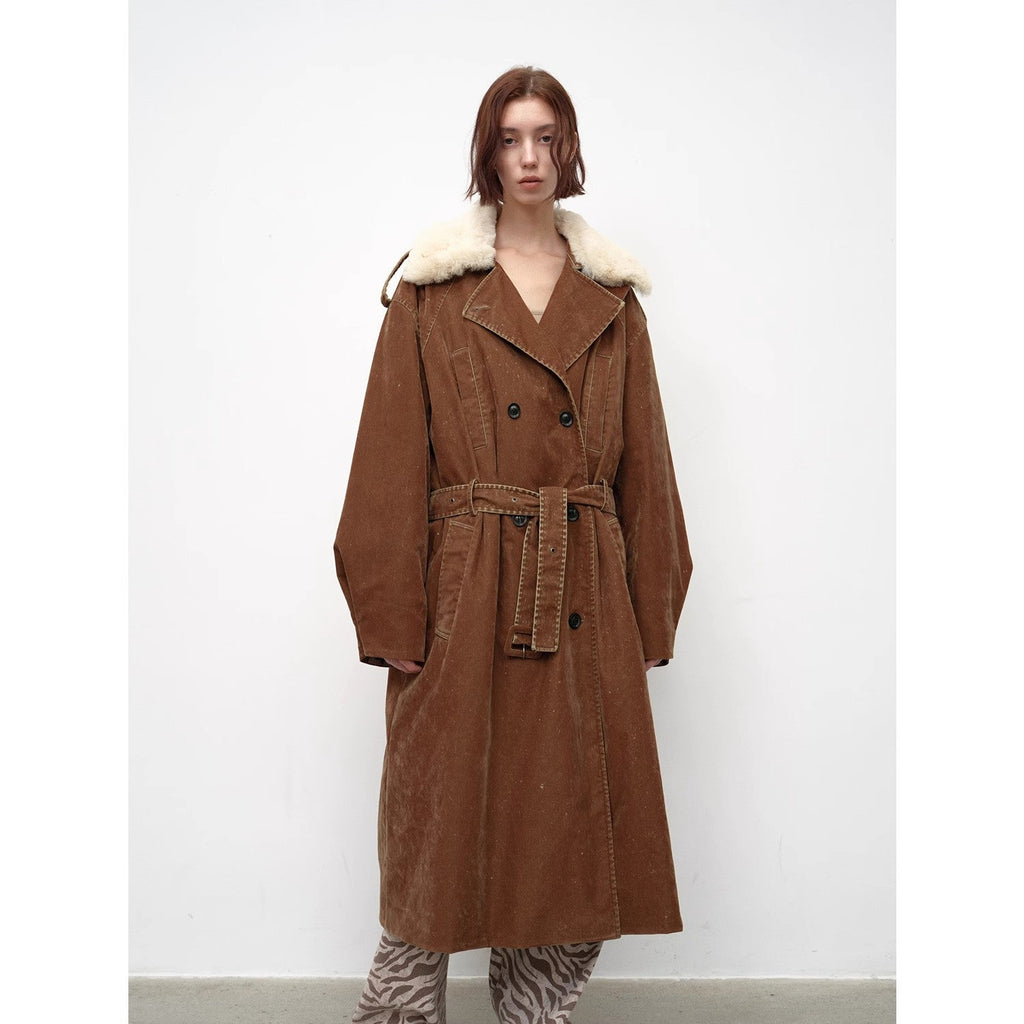 Person wearing a brown coat with white fur trim on a white background