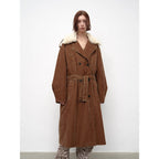 Person wearing a brown coat with white fur trim on a white background
