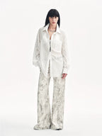 Person wearing a white shirt and patterned pants on a white background