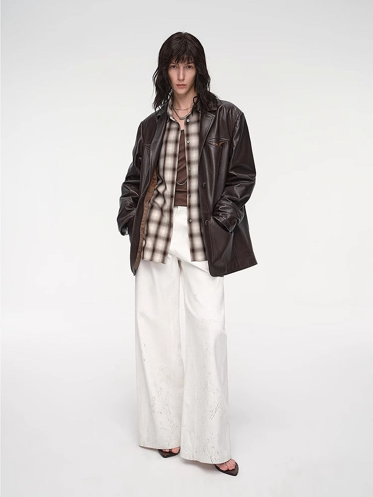 Person wearing a brown jacket, plaid shirt, and white pants on a white background