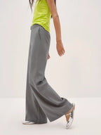 Person wearing gray wide-leg pants and a bright green top on a white background