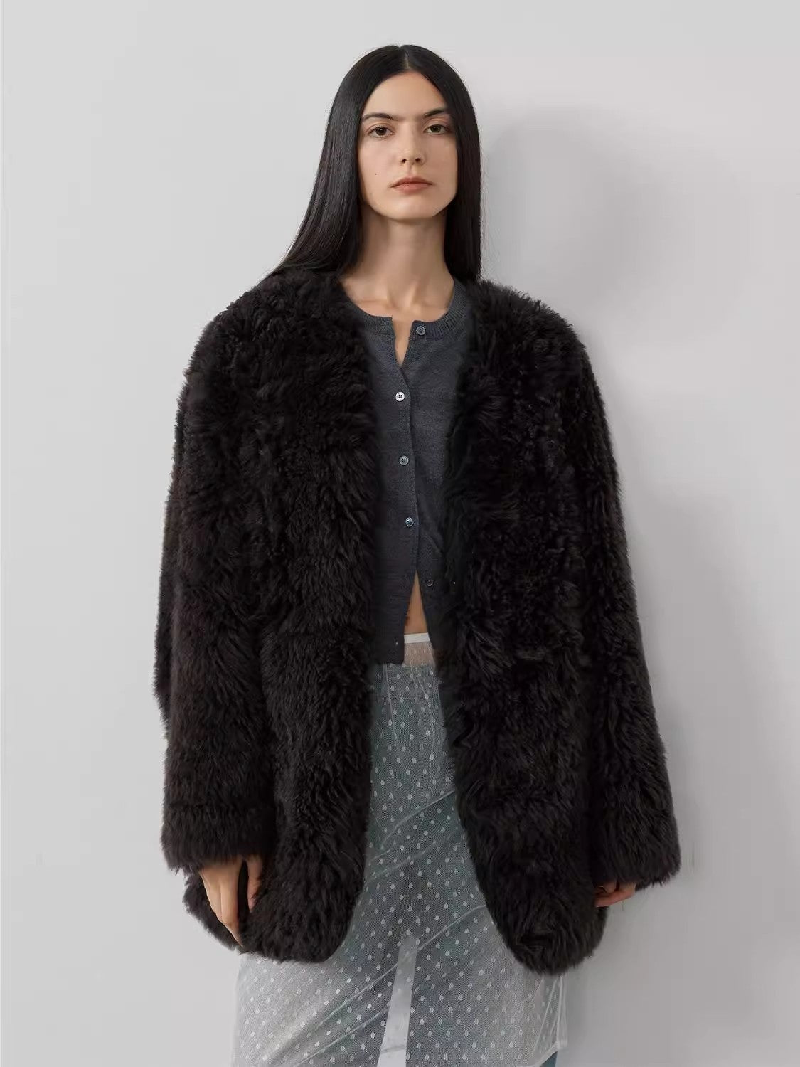Woman wearing a black fluffy coat against a plain background