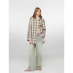 Woman wearing a plaid shirt and light green pants on a white background