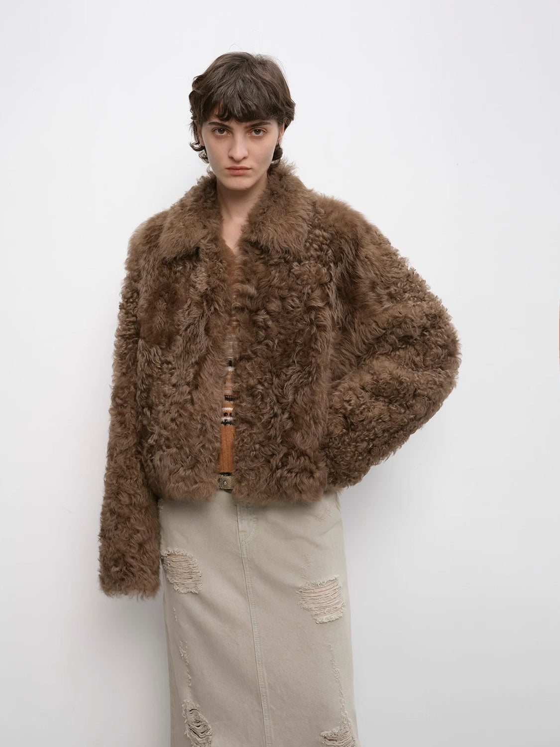 Person wearing a brown fluffy jacket on a white background