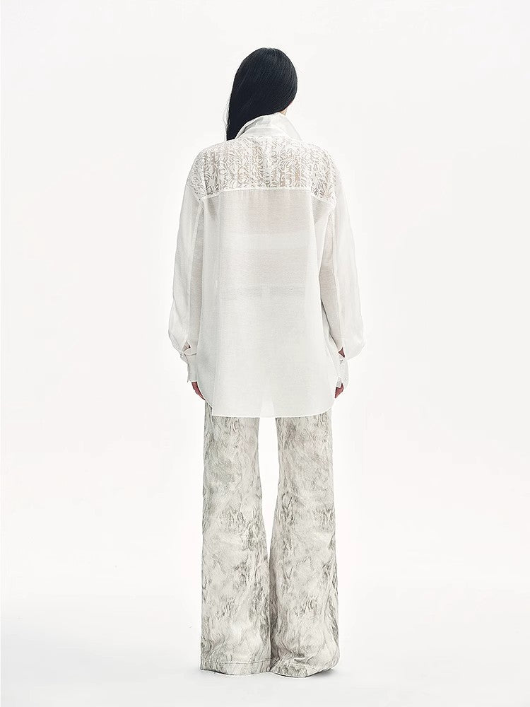 Person wearing a white lace-trimmed blouse and patterned pants on a white background