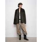 Person wearing a dark fur coat, light pants, and black boots against a white background