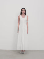 Woman wearing a white sleeveless dress against a plain background