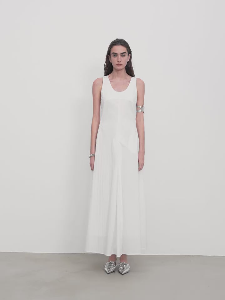Woman wearing a white sleeveless dress against a plain background