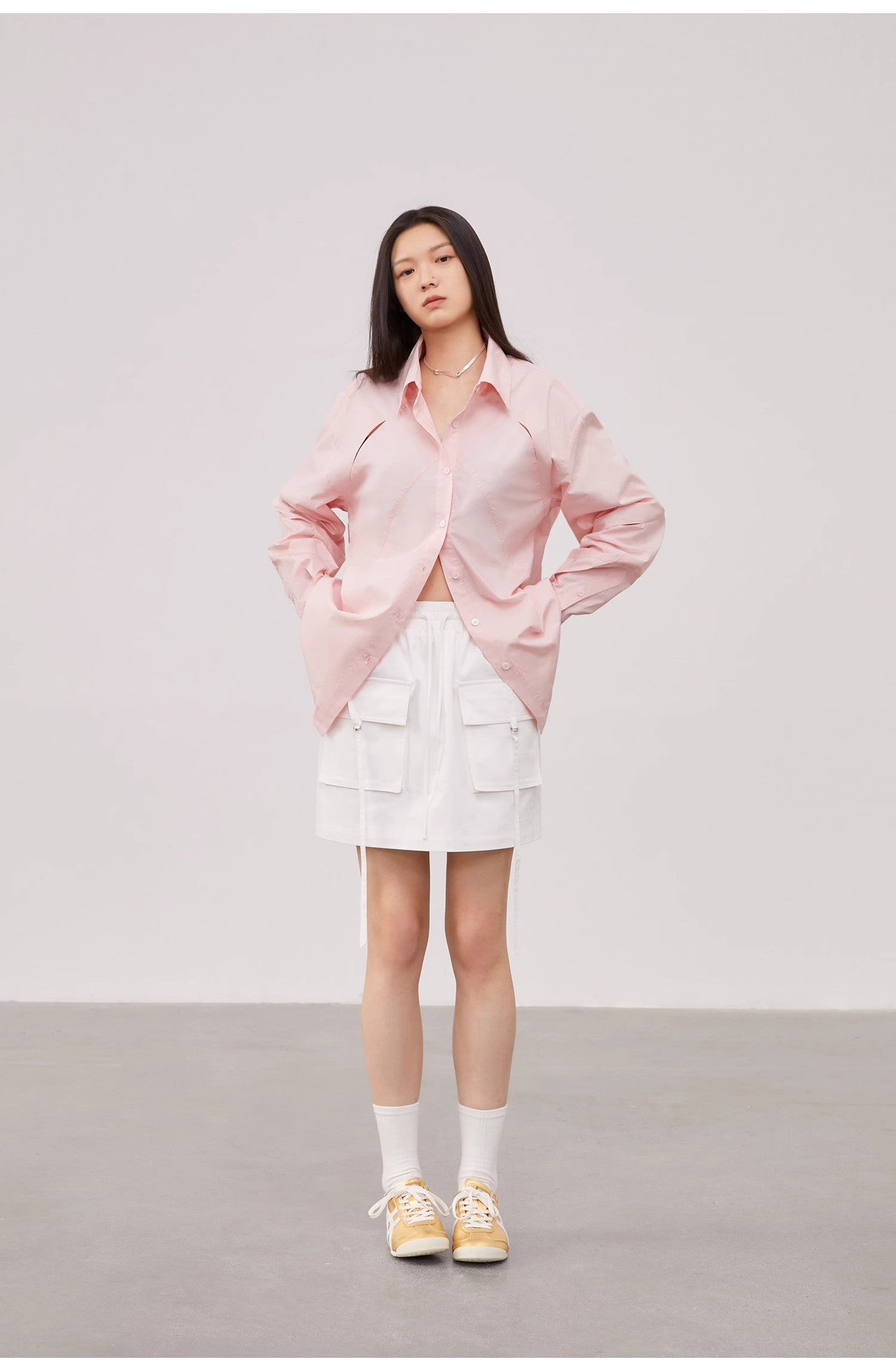 Person wearing a pink jacket and white skirt on a plain background