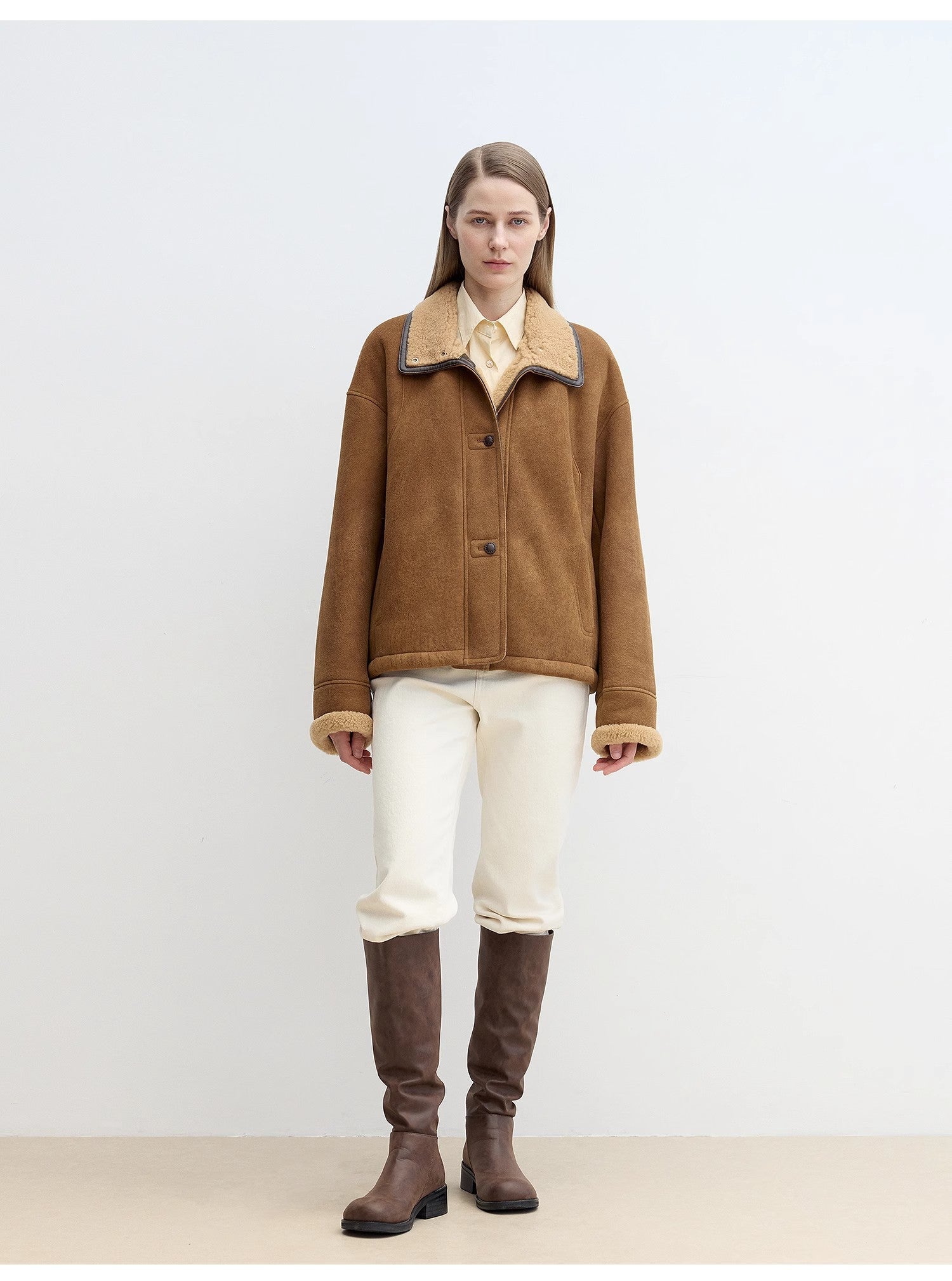 Person wearing a brown jacket and knee-high brown boots on a white background