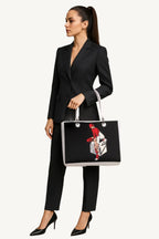 Woman in a black suit holding a tote bag with a graphic design on a beige background