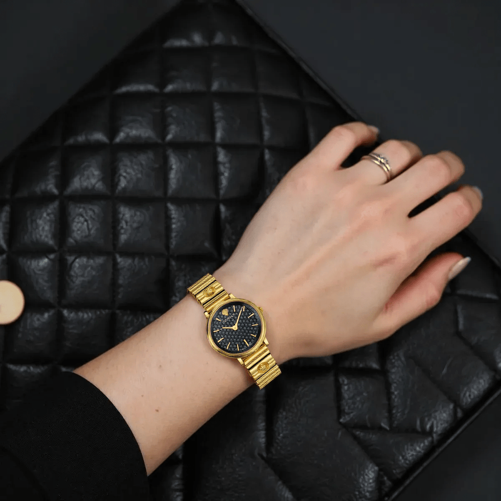 Versace VE8101519 V-Circle ladies watch with silver-tone dial, gold-tone stainless steel case, Greca pattern bezel, and black leather strap with Medusa logo.