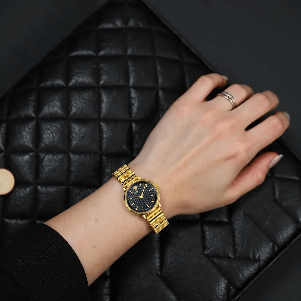 Versace VE8101519 V-Circle ladies watch with silver-tone dial, gold-tone stainless steel case, Greca pattern bezel, and black leather strap with Medusa logo.