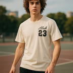 Person wearing a beige t-shirt with 'Alessi 23' on a sports field