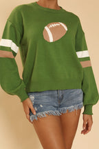 Green sweater with football design and white stripes on a beige background