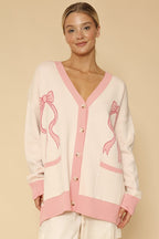 Woman wearing a cream cardigan with pink accents on a beige background