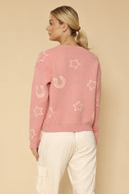 Woman wearing a pink sweater with star patterns on a beige background