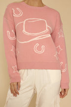Pink sweater with white graphic designs on a beige background