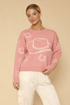 Woman wearing a pink sweater with white patterns on a beige background