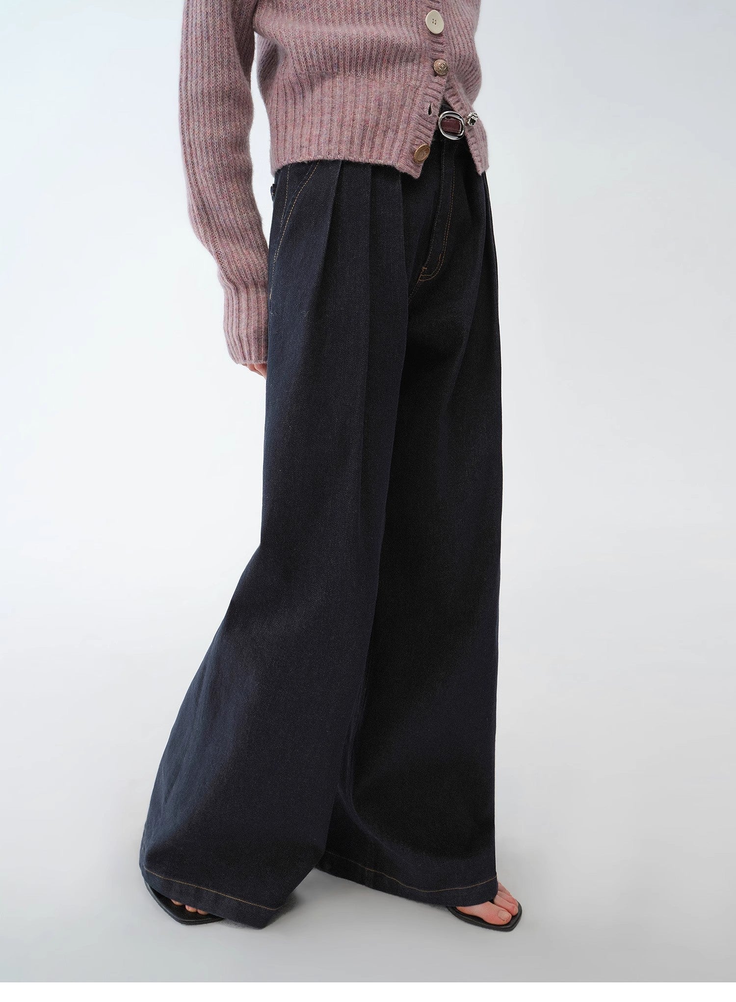Person wearing a pink ribbed sweater and black wide-leg pants on a white background