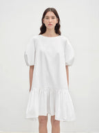 Woman wearing a white dress against a plain background