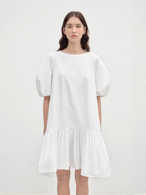 Woman wearing a white dress against a plain background