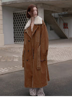 Person wearing a long brown coat with white fur lining in an urban setting