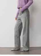 Person wearing a purple sweater and gray wide-leg jeans against a plain background