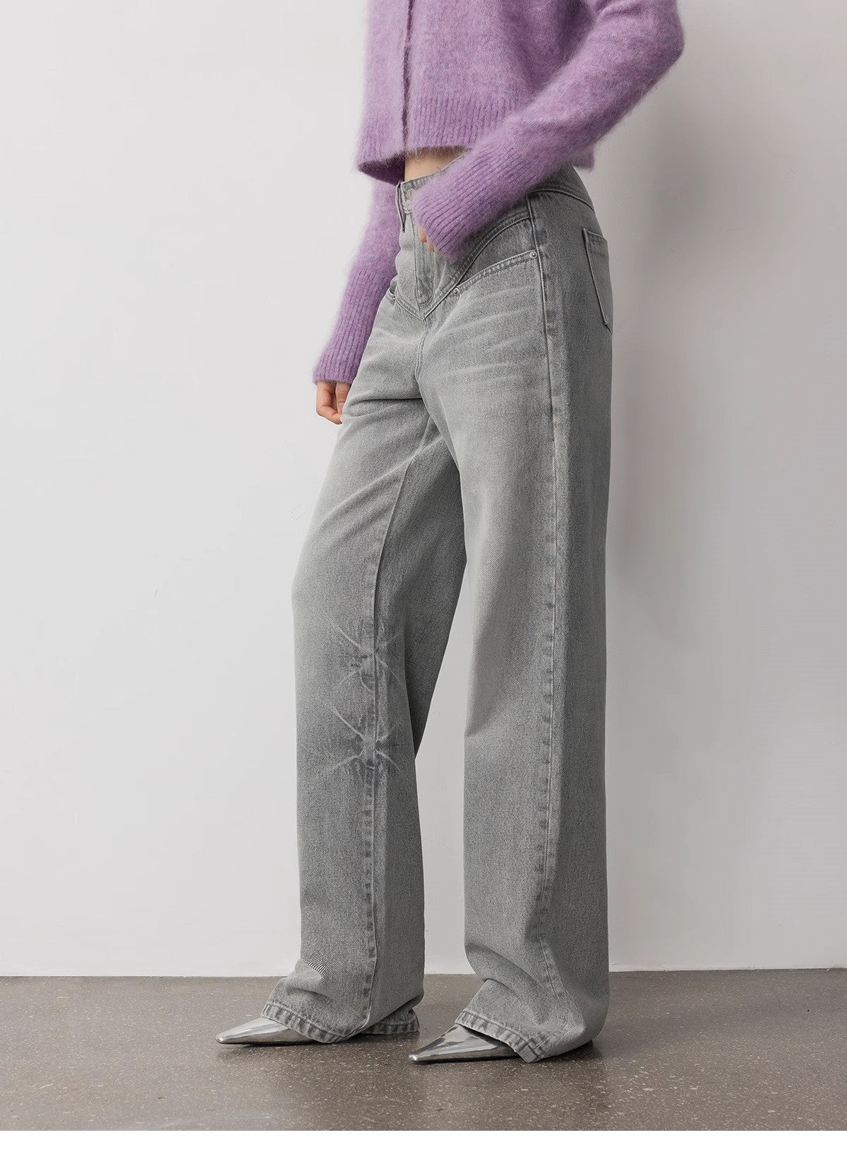 Person wearing a purple sweater and gray wide-leg jeans against a plain background