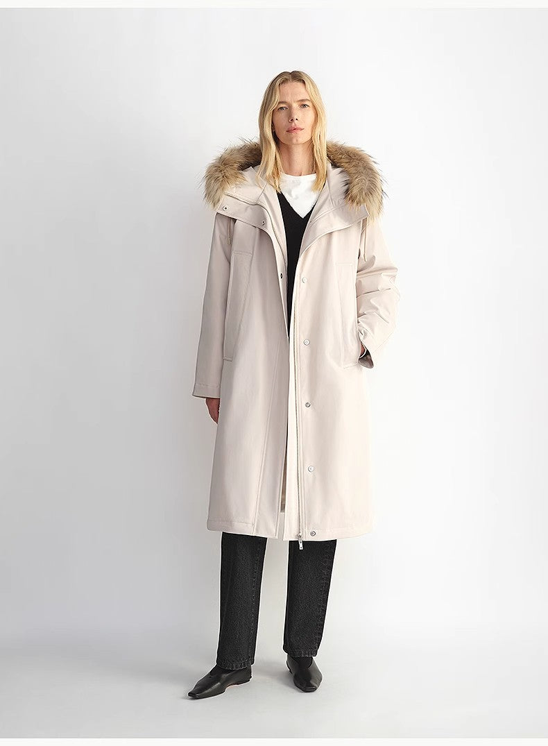 Woman wearing a long beige coat with fur hood on a white background