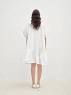 Woman wearing a white dress standing against a plain white background