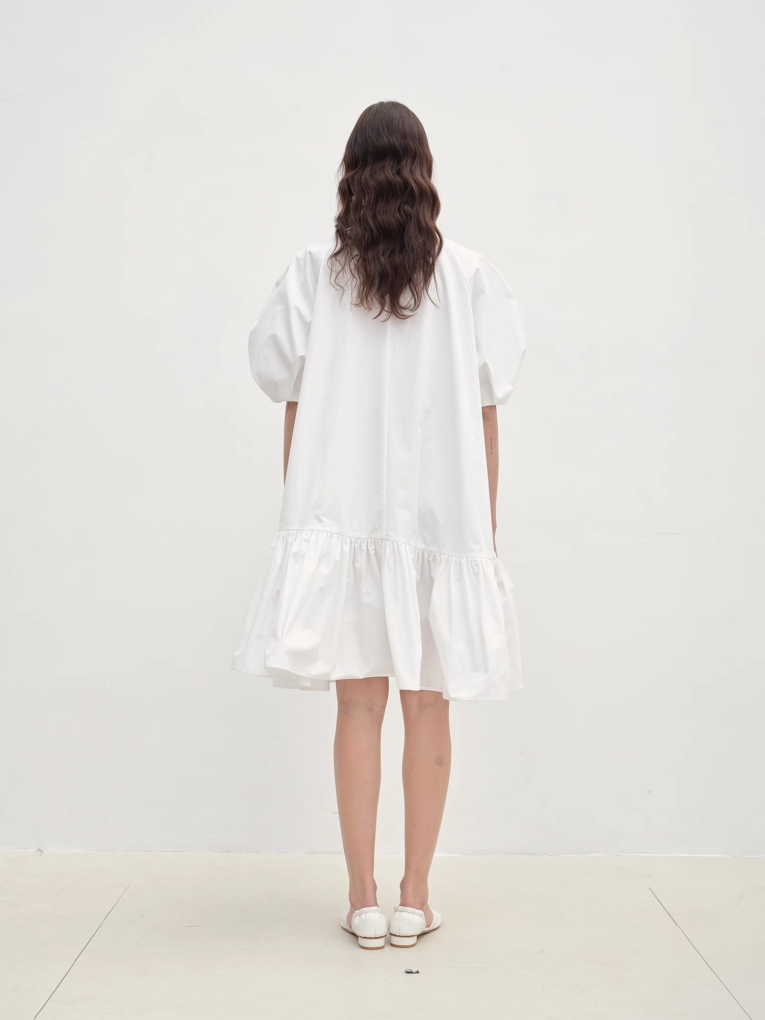 Woman wearing a white dress standing against a plain white background