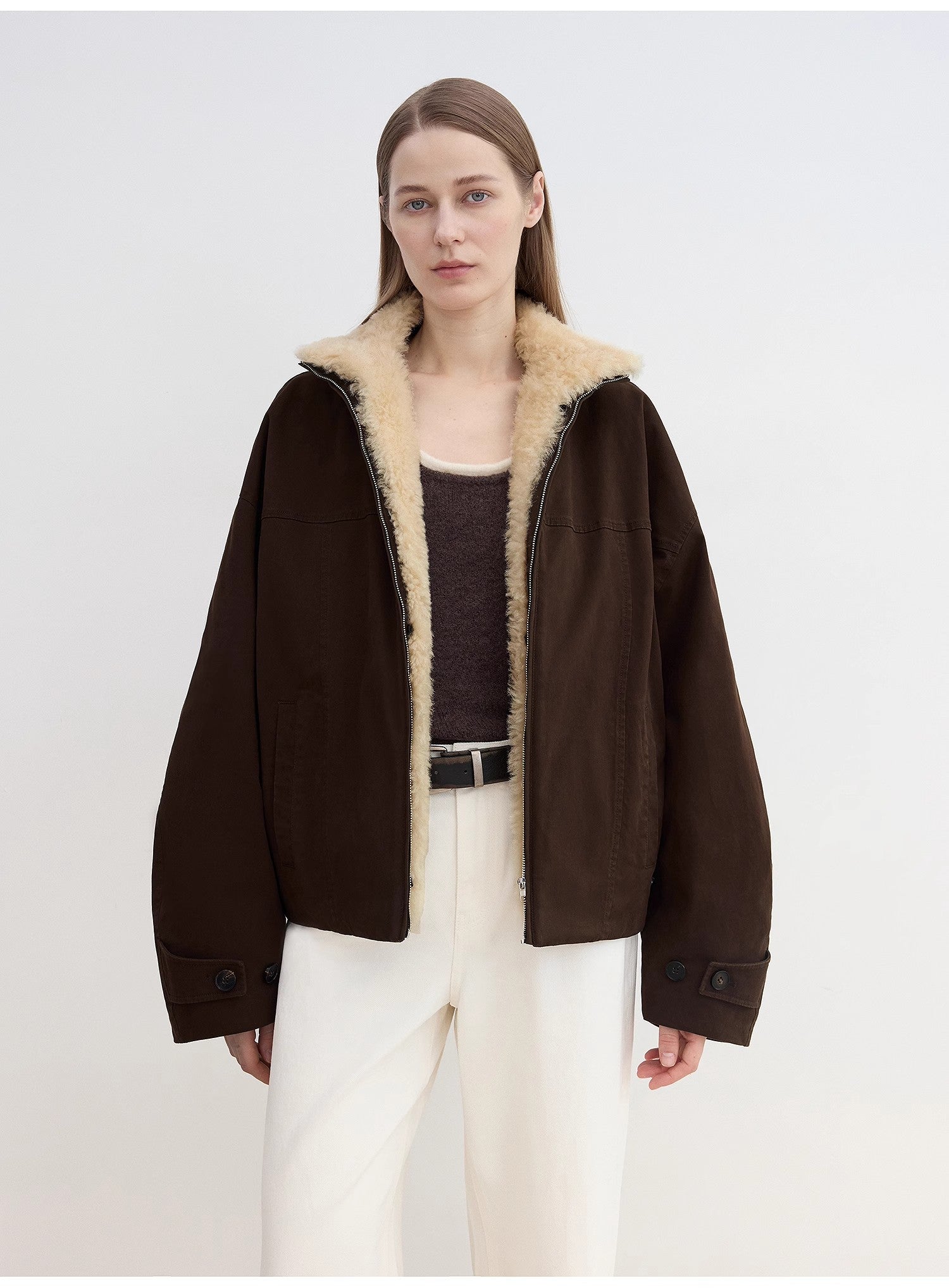 Woman wearing a brown jacket with beige fur lining on a white background