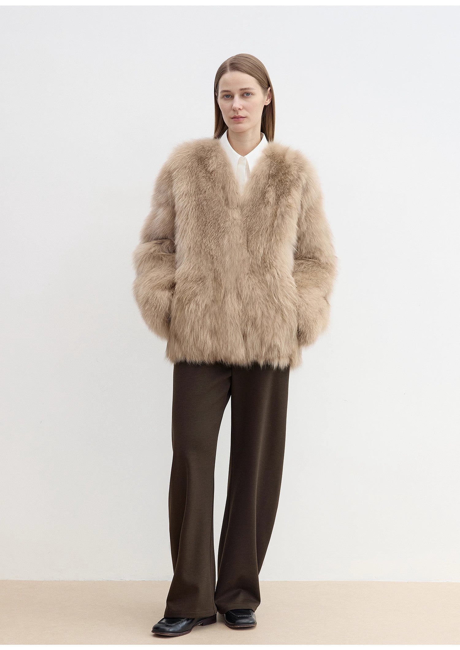 Person wearing a beige fluffy coat on a plain background